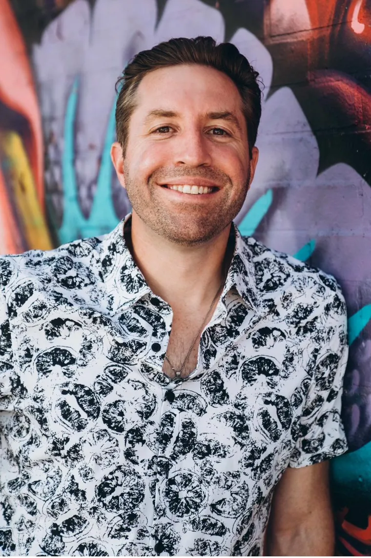 Rob Cressy smiling in front of a colorful mural